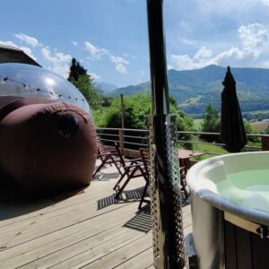 Terrasse bulle transparente avec jacuzzi et parasol.