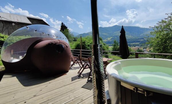 Terrasse bulle transparente avec jacuzzi et parasol.