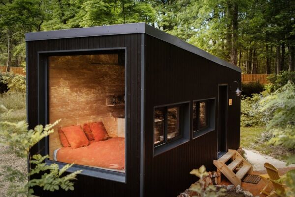 Tiny house en forêt vu de 3/4 avec grande vitre.